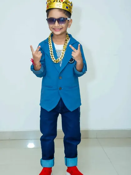 This young man is rocking the party look with a crown, sunglasses, and a thick gold chain prop. It's all about having fun and expressing yourself.