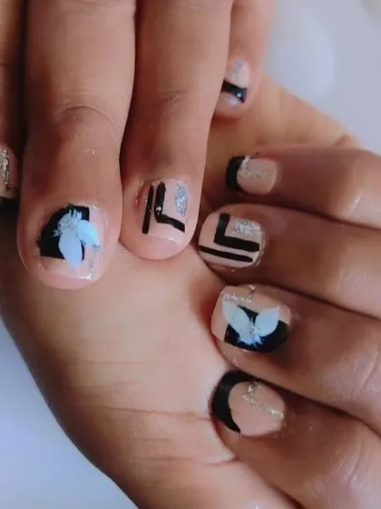 This is a custom toe nail art design I created, combining a few different styles. It has a clean nude base with bold black geometric shapes, delicate 3D white flower details, and fine silver glitter lines for a little sparkle.