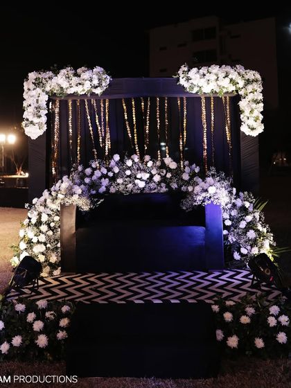 A chic black and white themed seating area for the couple, featuring a dramatic floral arch and a modern patterned floor.