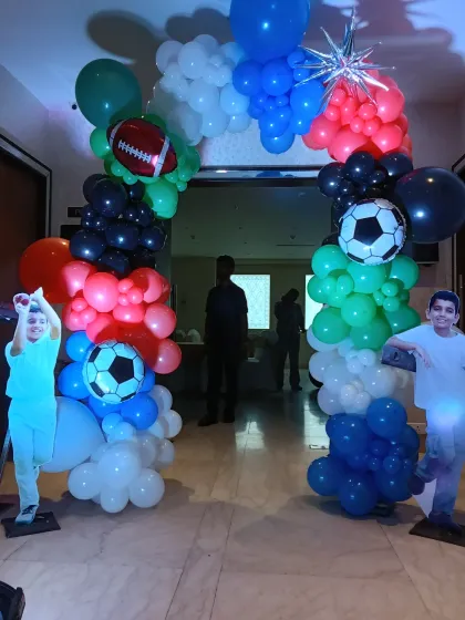 An action-packed entrance arch for a sports-themed birthday party. The arch is made of colorful balloons and decorated with football and rugby ball foils, with cutouts of the birthday boys.