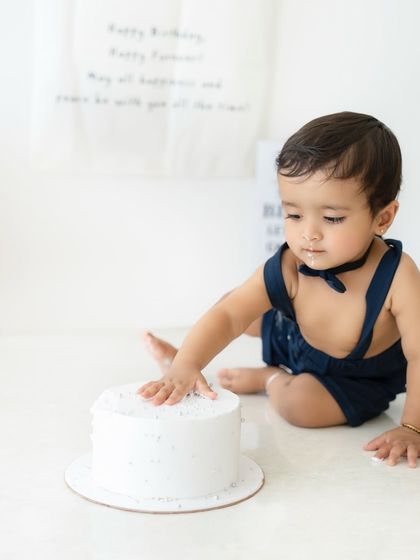 The first touch. This photo captures the gentle curiosity as the birthday boy reaches out to feel his very first cake.