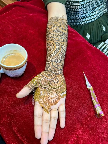 A perfect combination: a cup of tea and a freshly done bridal mehendi. This shot shows the back of a hand with a beautiful, flowing paisley design.