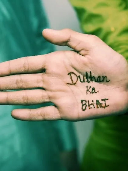A creative mehendi shot showing "Dulhan ka Bhai" written on a hand, capturing the fun family moments.