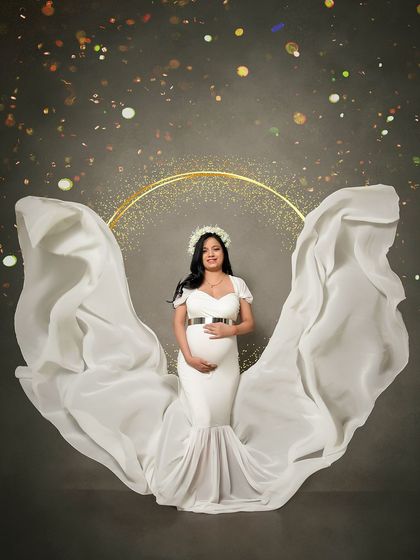 A classic angel-wing fabric toss with a beautiful white gown. This solo portrait against a dark, sparkling backdrop creates a timeless and ethereal image of the mother-to-be.