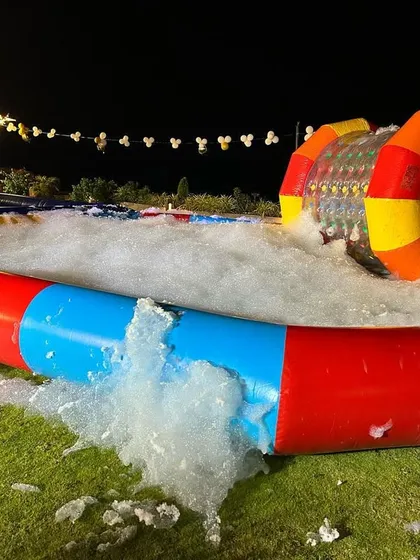 A full foam party setup showing the inflatable pool filled with foam. You can see a water zorbing roller in the background, showing how activities can be combined.