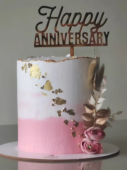 Sometimes, simplicity is the ultimate statement. This anniversary cake features a soft pink and white watercolor effect in buttercream, accented with a touch of edible gold leaf and delicate dried florals for a minimalist yet romantic feel.