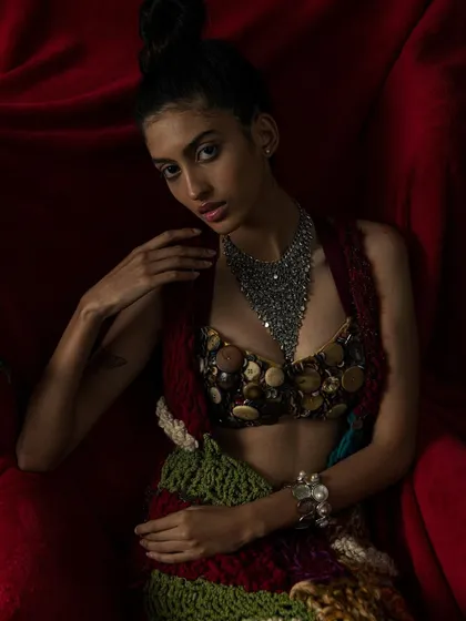 A powerful portrait where the model's direct gaze contrasts with the soft, enveloping fabric of the chair.