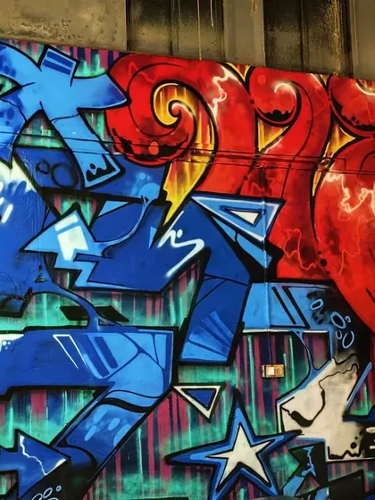A closer look at the details in the Red Bull 'Dance Your Style' mural. The sharp blue geometric forms contrast with the fiery red swirls, creating a visual representation of technique and flow.