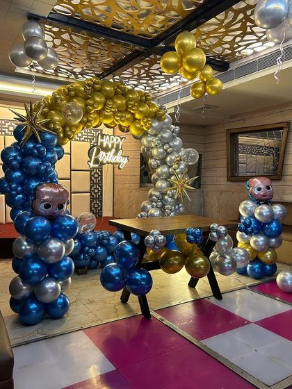 A different angle of the Boss Baby themed party, showing the balloon sculptures and the elegant gold, blue, and silver color scheme.