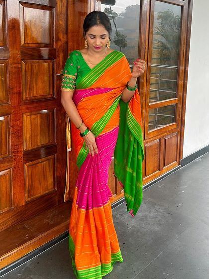 A client in a colorful orange, pink, and green saree. The custom green blouse has delicate embroidery on the sleeves.
