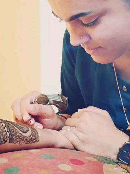 A candid photo of me focused on my work. Applying mehendi is a meticulous process, and I pour my heart into every design I create.