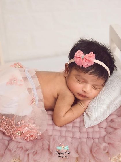 Details matter. This little one is sleeping peacefully on a tiny bed prop, dressed in a delicate lace and pearl skirt for an elegant touch.