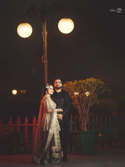 A full-length portrait of the couple under a lamppost. This classic, posed shot highlights their elegant evening wear and the romantic ambiance of the night.