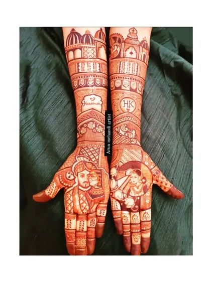 This bridal mehndi design features detailed portraits of the bride and groom, along with their initials, set against a backdrop of royal architecture, symbolizing their palace of love.