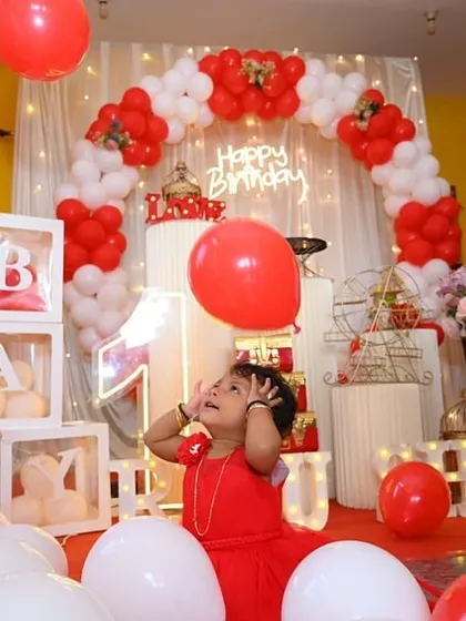 A candid shot of the birthday girl looking up in wonder at the balloons during her red and white themed first birthday party.
