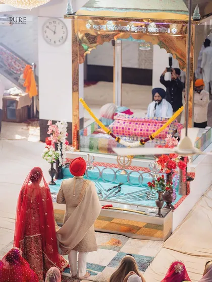 A view from behind the couple as they face the Guru Granth Sahib. This angle provides a unique perspective on the sacredness of the Anand Karaj.