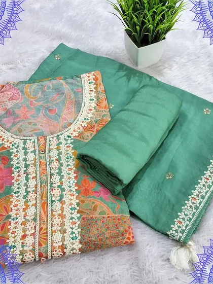 A beautiful green dress material set with a digital print top featuring patchwork-style Kalamkari motifs. The simple dupatta has a delicate lace border, balancing the look perfectly.