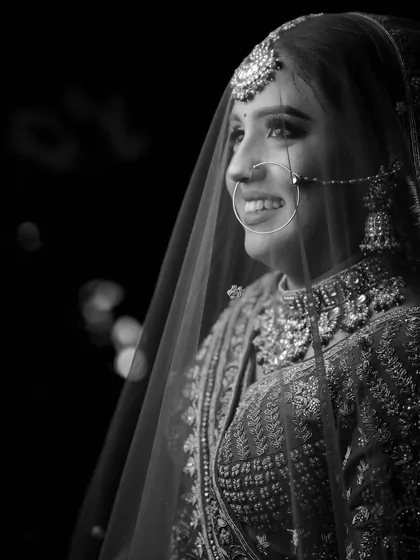 A timeless black and white bridal portrait, where the focus is purely on her happy expression and the silhouette of her veil.
