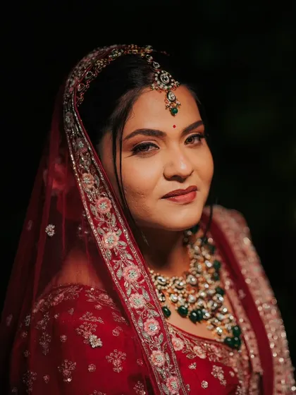 A dramatic and captivating bridal portrait. For this Varamala look, I created a defined, smokey eye and a bold lip to match the richness of the bride's red and emerald ensemble, ensuring she looked like a queen.
