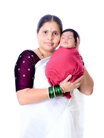 A tender portrait of a grandmother holding her newborn grandchild, both wrapped in traditional attire.