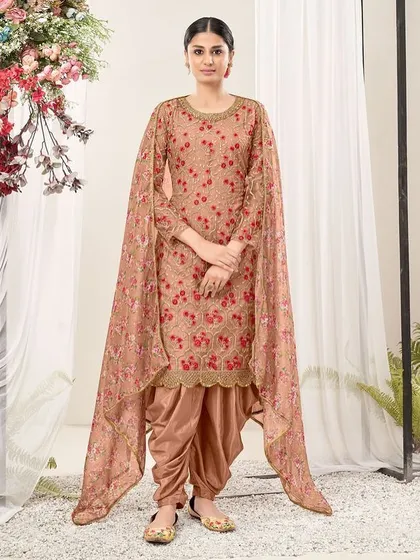 A modern take on a classic Punjabi suit. This chiku and pink net suit features a cape-style dupatta and dhoti pants, perfect for someone who loves to experiment with their style.