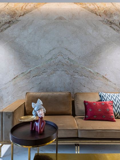A close-up of the sofa in the Filigree House, set against a stunning book-matched marble wall. This detail showcases the interplay of textures, from the soft fabric to the cool, dramatic stone.