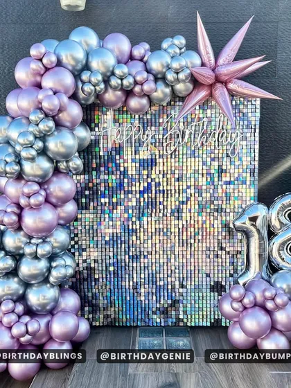 A stylish 18th birthday party with an iridescent shimmer wall. The lavender and silver balloon arch and foil '18' balloons create a chic and modern look.