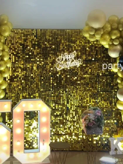 Celebrating a fabulous 50th birthday with glamour and style. This photo booth setup features a shimmering gold sequin wall, a custom neon "Happy Birthday" sign, a large marquee number "50", and a coordinating gold and black balloon arch.