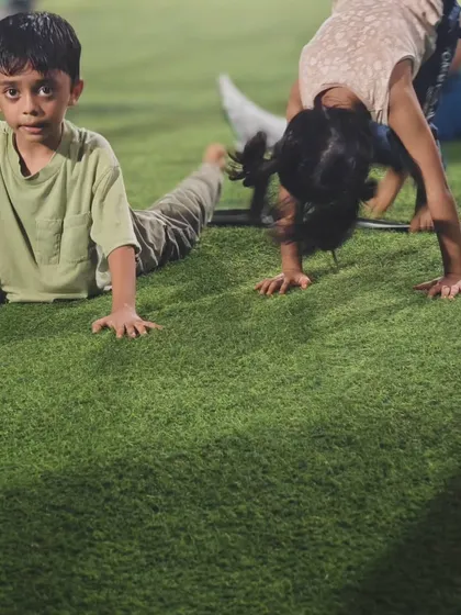 A young boy and girl practice their stretches together. We encourage a supportive environment where kids learn the importance of flexibility for overall fitness.