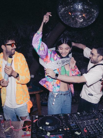 My friends surprising me with a "Happy Birthday" sash at my party. My events are all about community, and I'm so grateful for the people who support me.