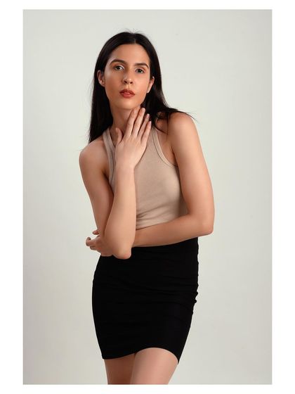 A clean studio shot of a model in a beige tank top and black skirt. This is a classic lookbook style, perfect for showcasing wardrobe staples.
