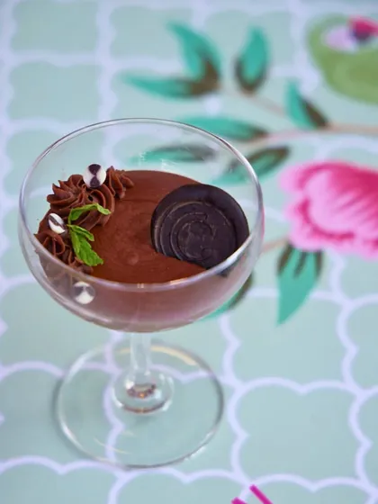 A beautifully composed chocolate mousse dessert in a coupe glass. The smooth mousse is garnished with fresh mint, making it as elegant to look at as it is to eat.