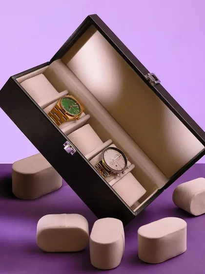 A creative, "deconstructed" shot of a watch box with its pillows floating around it. The purple background adds a pop of color, making this a playful and modern take on a classic product.