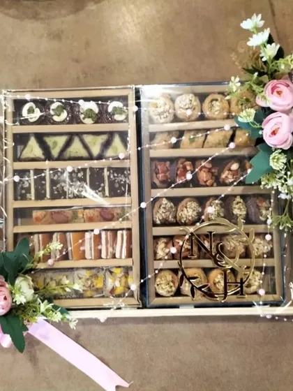 Our gourmet gifting services include beautifully arranged trays of traditional Indian sweets. This mithai hamper, presented in sectioned wooden boxes with a custom monogram, is a perfect example of our elegant food packaging solutions.