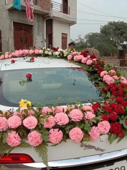 A rear view of a car decorated with pink carnations and red roses. The floral arrangement cascades down the back, ensuring the car looks beautiful from every angle.