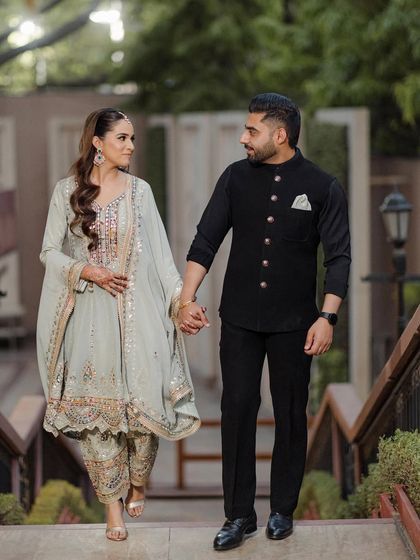 Anisha and Abhishek walking hand-in-hand down a flight of stairs, a classic and elegant engagement portrait.