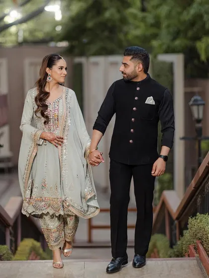 Anisha and Abhishek walking hand-in-hand down a flight of stairs, a classic and elegant engagement portrait.
