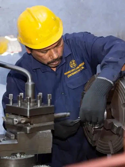A close-up shot of a factory worker operating a lathe machine. My focus here is on capturing the concentration and technical skill of the employee in their work environment.