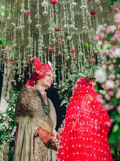 An intimate moment between the couple under the floral canopy of the Varmaala mandap. The cascading jasmine and rose strings create a beautiful, fragrant veil around them.