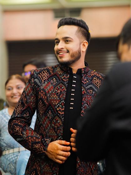 Surrounded by friends and family, this groom is the center of attention. His unique jacket and sharp haircut make him stand out.