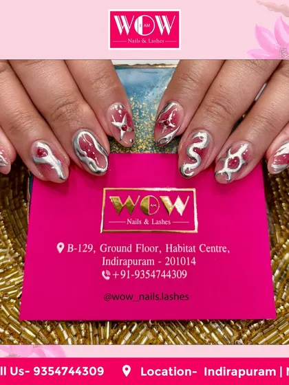 A bold and creative design featuring a sheer base with 3D metallic silver and red abstract art. This look is perfect for someone who wants their nails to be a conversation starter.