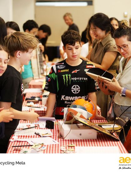A student explains his upcycled product to an interested parent. The mela provided a real-world context for learning about economics and environmental responsibility.