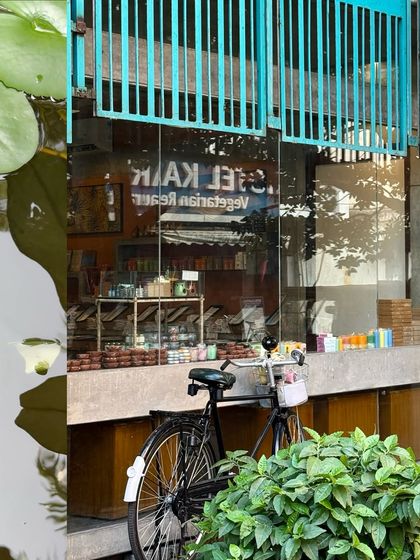 A bicycle parked outside a cafe, its reflection captured in the glass of a large window.