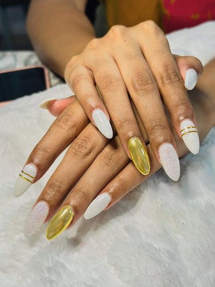 An elegant set of white nails accented with gold chrome and sugar glitter for a mix of textures.