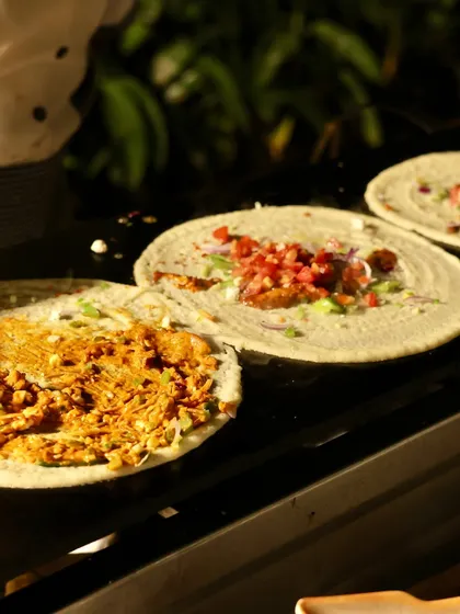 Another angle of my live dosa station, showing different varieties being prepared side by side. You can see a classic masala filling on one and a cheesy vegetable mix on another, highlighting the customization I offer.