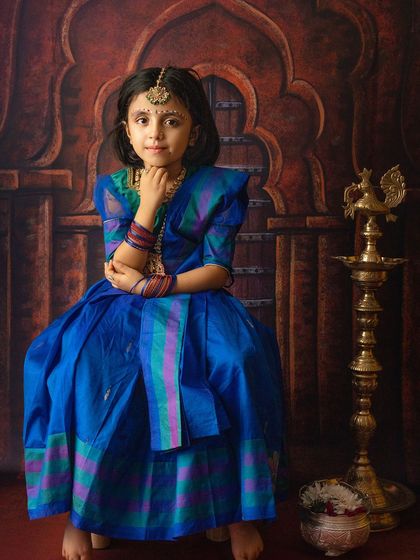 A beautiful portrait of a young girl dressed in a traditional blue saree, representing Radha, in a classic, elegant pose.