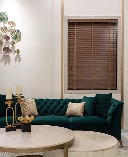 The drawing room from the same project, featuring our deep green tufted chesterfield sofas and nested marble-topped coffee tables.