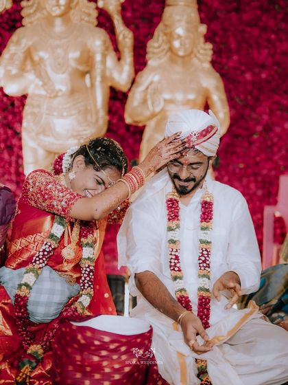 A playful moment during the wedding ceremony, the bride smiling as she participates in a ritual with the groom.