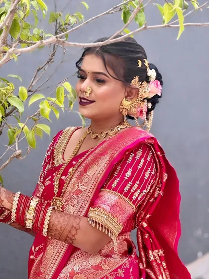 A side profile showcasing the intricate floral hair bun and jewellery. The hairstyle is decorated with fresh flowers and a traditional 'ambada' pin, essential for a Maharashtrian bride.
