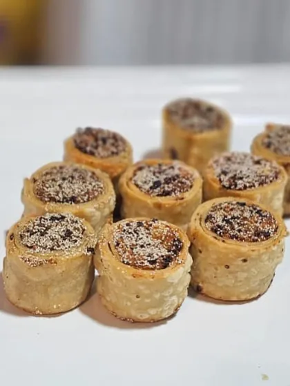 These are baked savory rolls, a modern take on a traditional snack. They are filled with a spiced mixture and offer a delightful crunch, perfect as a pass-around appetizer.
